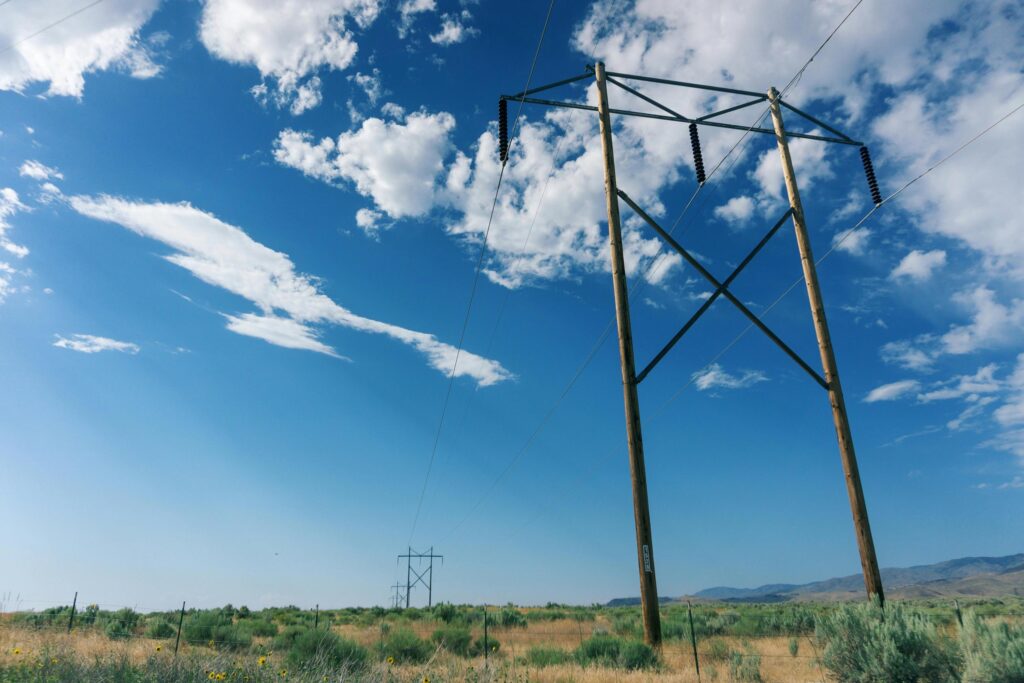 A line of small electric transmission towers crossing a flat plane with the short mountains in the distance to the right.
